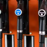 Drei Zapfpistolen an einer orangefarbenen Tankstelle: Super 95 E5, Super E10 und Diesel B7.