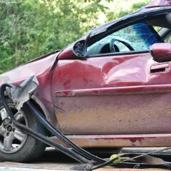 Schwer beschädigter roter Wagen, Windschutzscheibe zerbrochen. Ein trauriges Zeugnis eines Unfalls, vielleicht durch Alkohol verursacht.