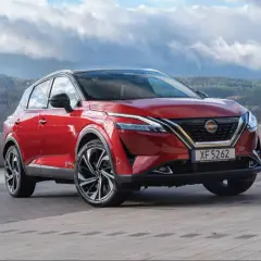Roter Nissan Qashqai vor einer bergigen Landschaft. Die Frage "woher kommt Nissan" wird durch die Herkunft des Autos beantwortet: aus Japan.