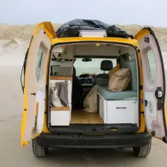 Gelber Campervan am Strand, innen gemütlich ausgebaut. Die Nachteile der Wohnmobil-Zulassung sind hier vergessen.