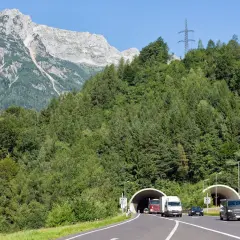 Autobahn mit Tunneln und Verkehr vor alpiner Bergkulisse. Die Fahrt durch den Tunnel könnte Teil der Liechtenstein Maut sein.