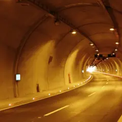Die A10 Tauernautobahn führt durch einen beleuchteten Tunnel. Die Straße ist nass, die Wände sind aus Beton und mit Lichtern versehen.