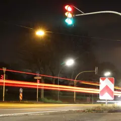 Rote Ampel, Blitzer, 2 mal geblitzt. Lichtspuren von Autos bei Nacht, rote Ampel leuchtet, Verkehrsschilder.