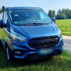 Blauer Campervan (Westfalia) steht auf einer Wiese neben einem Feldweg. Hoffentlich keine uebler i21 probleme auf der Reise!