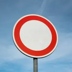 Verkehrsschild: Durchfahrt verboten, Strafe droht. Ein weißer Kreis mit rotem Rand vor blauem Himmel.