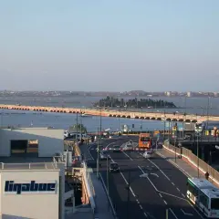 Autobahn nach Venedig mit dem Auto. Eine lange Brücke überspannt das Wasser, Autos und Busse fahren auf der Straße.