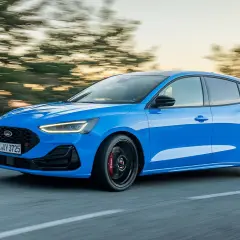 Ein blauer Ford Focus ST fährt auf einer Straße, die Bäume verschwimmen im Hintergrund.