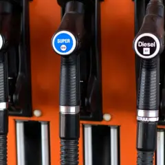 Drei Zapfpistolen an einer orangefarbenen Tankstelle: Super 95 E5, Super E10 und Diesel B7.