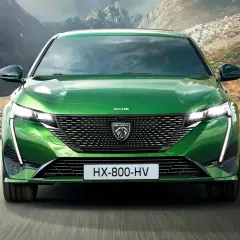 Grüner Peugeot 308 fährt auf einer Bergstraße. Breite Autos wie dieses bieten viel Platz und Komfort.