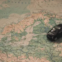 Kleines schwarzes Auto auf einer Europakarte. Die Reise beginnt, aber die Promillegrenze Frankreich ist zu beachten.
