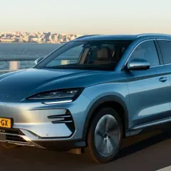 Ein blauer BYD fährt auf einer Brücke mit Stadtkulisse im Hintergrund. Die Bedeutung von BYD als führender Hersteller von Elektrofahrzeugen wird hier deutlich.
