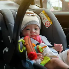 Ein Baby im Kindersitz vorne im Auto. Die Frage "ab wann darf ein Kind vorne sitzen" ist hier relevant, da es auf die richtige Sicherung ankommt.
