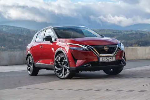 Roter Nissan Qashqai vor einer bergigen Landschaft. Die Frage "woher kommt Nissan" wird durch die Herkunft des Autos beantwortet: aus Japan.