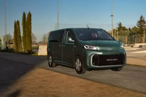 Ein grüner Van, der Toyota Proace Verso, fährt auf einer Straße. Dieses Van-Auto ist perfekt für Familienausflüge.