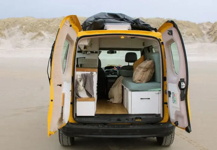 Gelber Campervan am Strand, innen gemütlich ausgebaut. Die Nachteile der Wohnmobil-Zulassung sind hier vergessen.