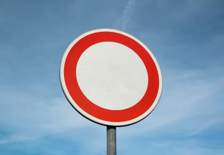 Verkehrsschild: Durchfahrt verboten, Strafe droht. Ein weißer Kreis mit rotem Rand vor blauem Himmel.