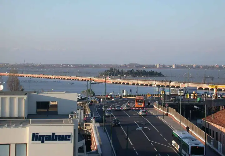 Autobahn nach Venedig mit dem Auto. Eine lange Brücke überspannt das Wasser, Autos und Busse fahren auf der Straße.