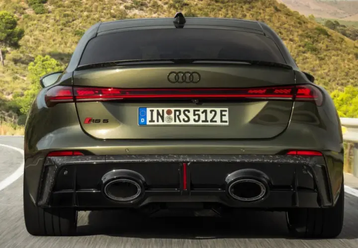 Ein Audi RS5 mit markantem Diffusor und ovalen Auspuffendrohren fährt auf einer kurvigen Straße.