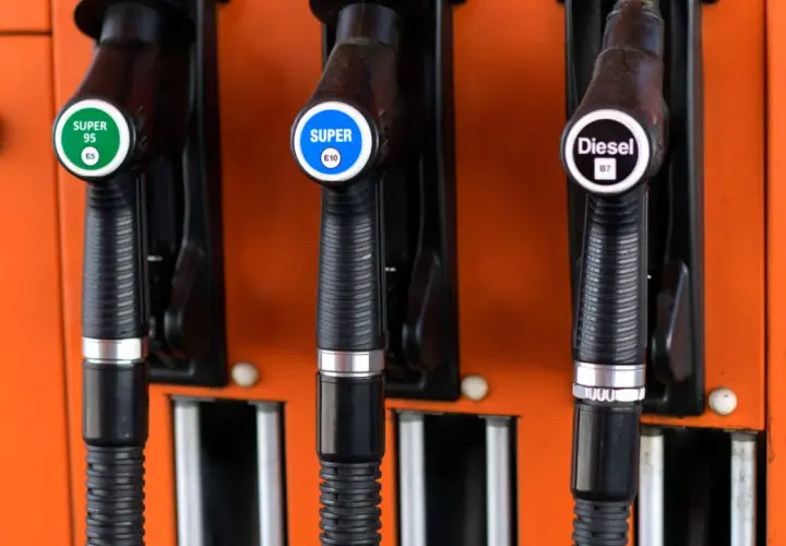Drei Zapfpistolen an einer orangefarbenen Tankstelle: Super 95 E5, Super E10 und Diesel B7.