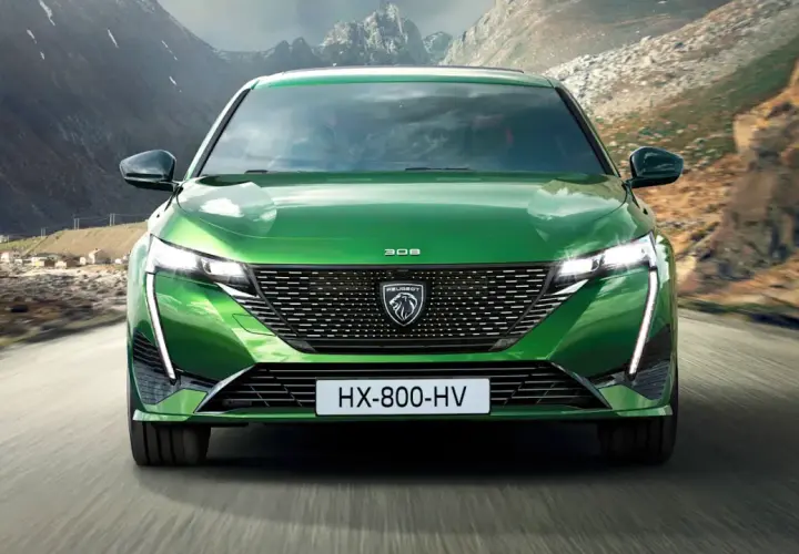 Grüner Peugeot 308 fährt auf einer Bergstraße. Breite Autos wie dieses bieten viel Platz und Komfort.