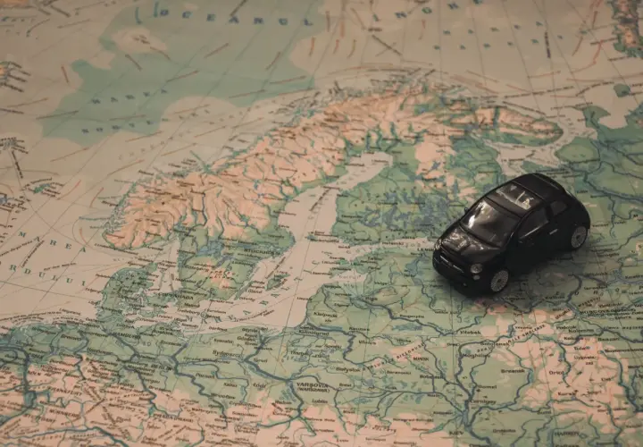 Kleines schwarzes Auto auf einer Europakarte. Die Reise beginnt, aber die Promillegrenze Frankreich ist zu beachten.