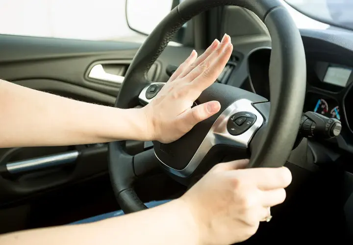 Hand drückt Hupe am Lenkrad. Darf man mit defekter Hupe fahren? Das ist eine wichtige Frage für die Verkehrssicherheit.