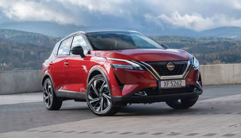 Roter Nissan Qashqai vor einer bergigen Landschaft. Die Frage "woher kommt Nissan" wird durch die Herkunft des Autos beantwortet: aus Japan.