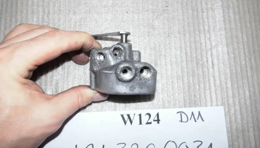 Metallteil für die Niveau Regulierung, gehalten von einer Hand.