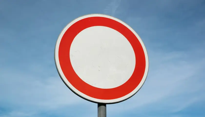 Verkehrsschild: Durchfahrt verboten, Strafe droht. Ein weißer Kreis mit rotem Rand vor blauem Himmel.