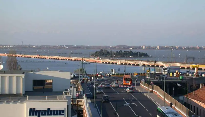 Autobahn nach Venedig mit dem Auto. Eine lange Brücke überspannt das Wasser, Autos und Busse fahren auf der Straße.