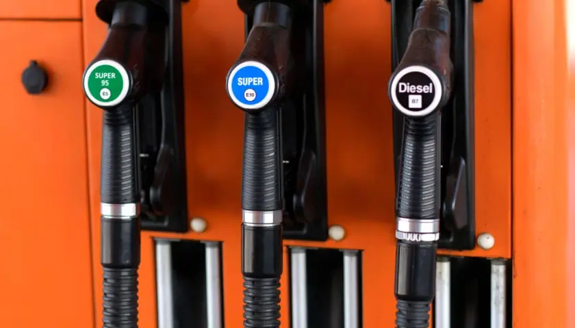 Drei Zapfpistolen an einer orangefarbenen Tankstelle: Super 95 E5, Super E10 und Diesel B7.