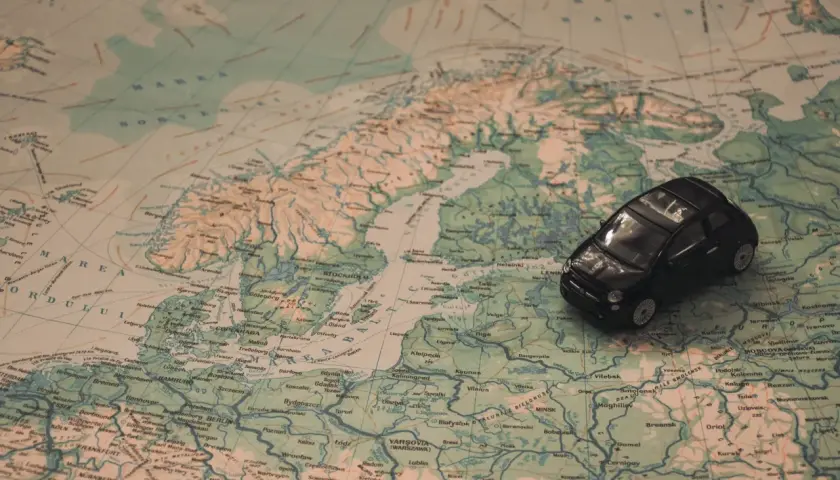 Kleines schwarzes Auto auf einer Europakarte. Die Reise beginnt, aber die Promillegrenze Frankreich ist zu beachten.