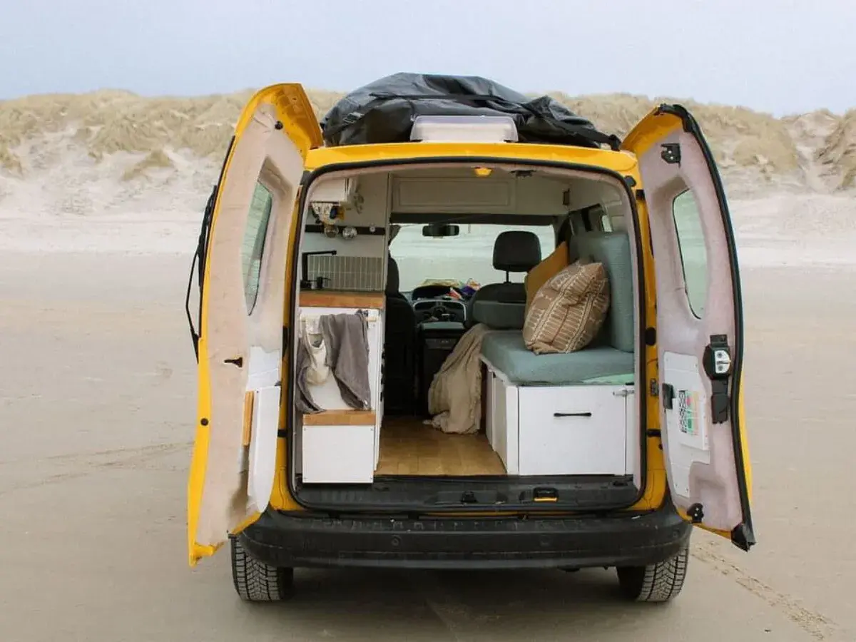 Gelber Campervan am Strand, innen gemütlich ausgebaut. Die Nachteile der Wohnmobil-Zulassung sind hier vergessen.