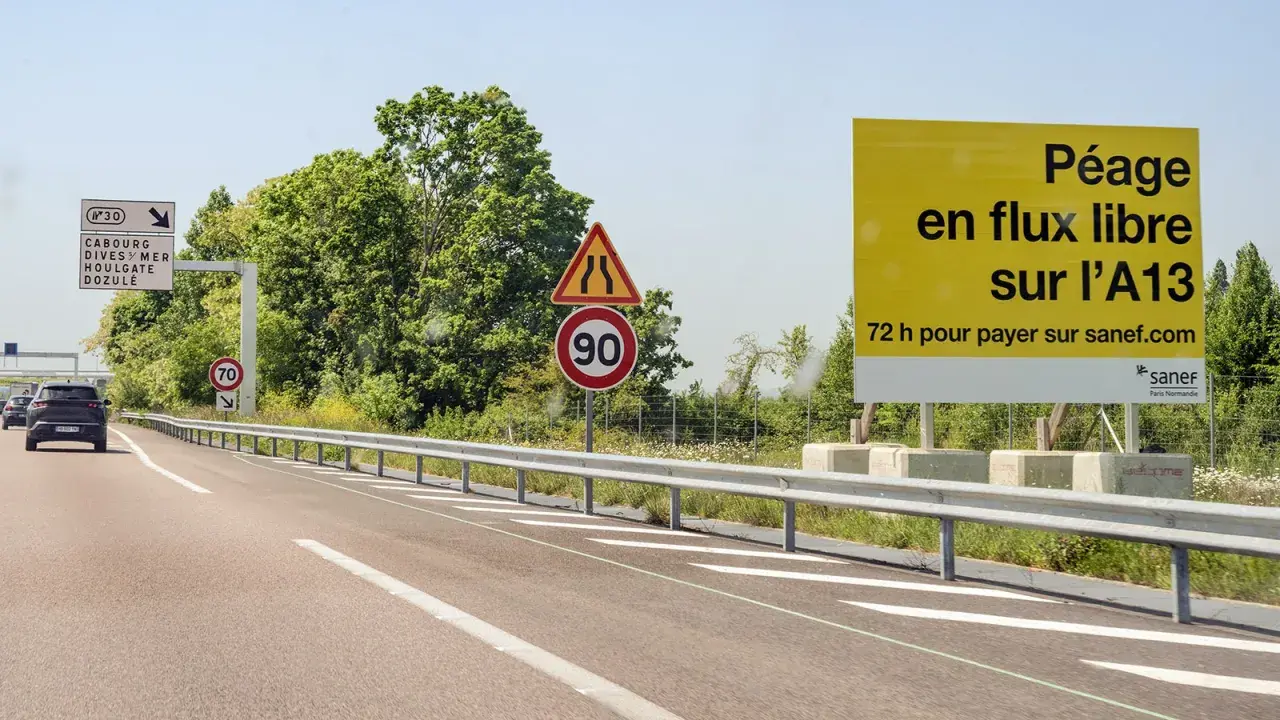 Autobahn in Frankreich mit Schildern für Mautstationen. Ein gelbes Schild informiert über "Péage en flux libre sur l'A13".
