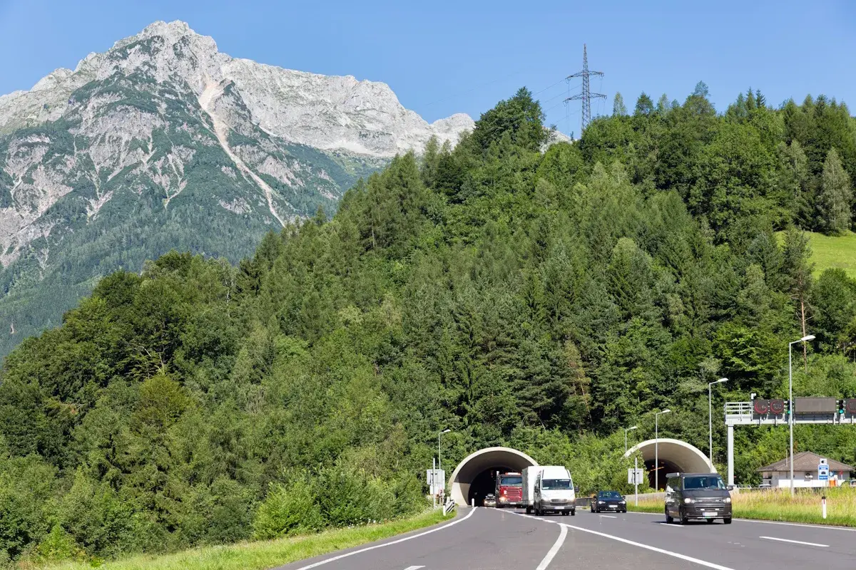 Autobahn mit Tunneln und Verkehr vor alpiner Bergkulisse. Die Fahrt durch den Tunnel könnte Teil der Liechtenstein Maut sein.