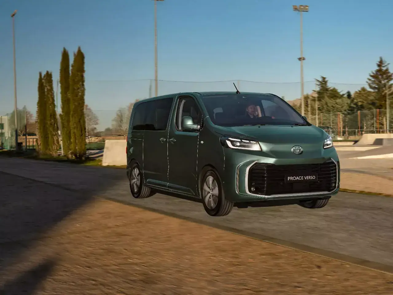 Ein grüner Van, der Toyota Proace Verso, fährt auf einer Straße. Dieses Van-Auto ist perfekt für Familienausflüge.