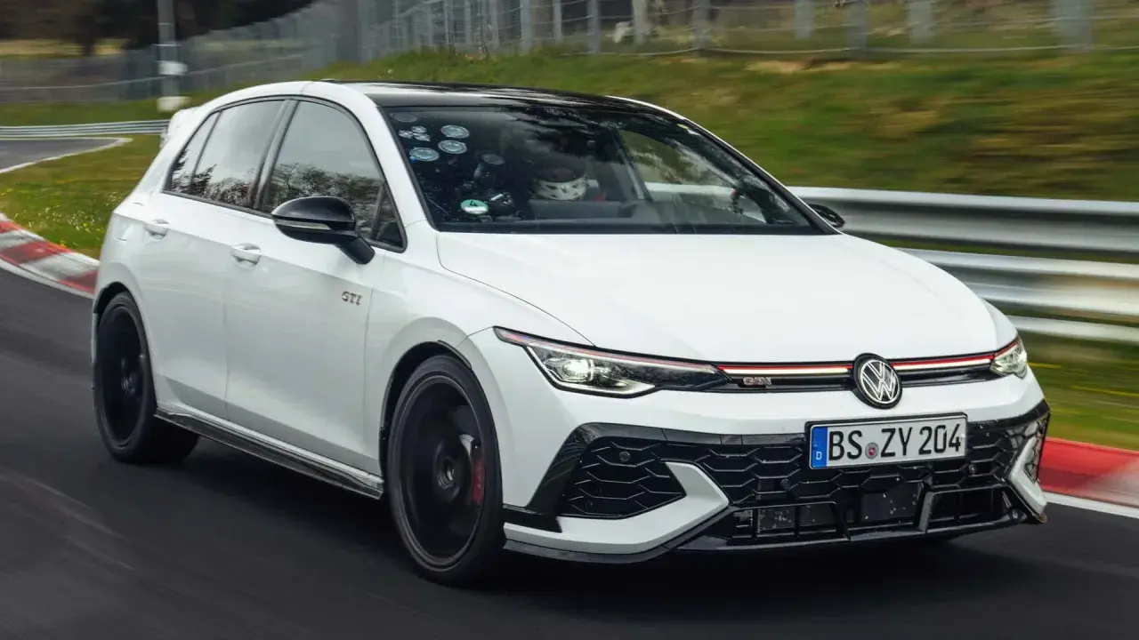 Weißer Golf GTI auf Rennstrecke, der Fahrer im Helm deutet auf den schnellsten Golf der Welt.