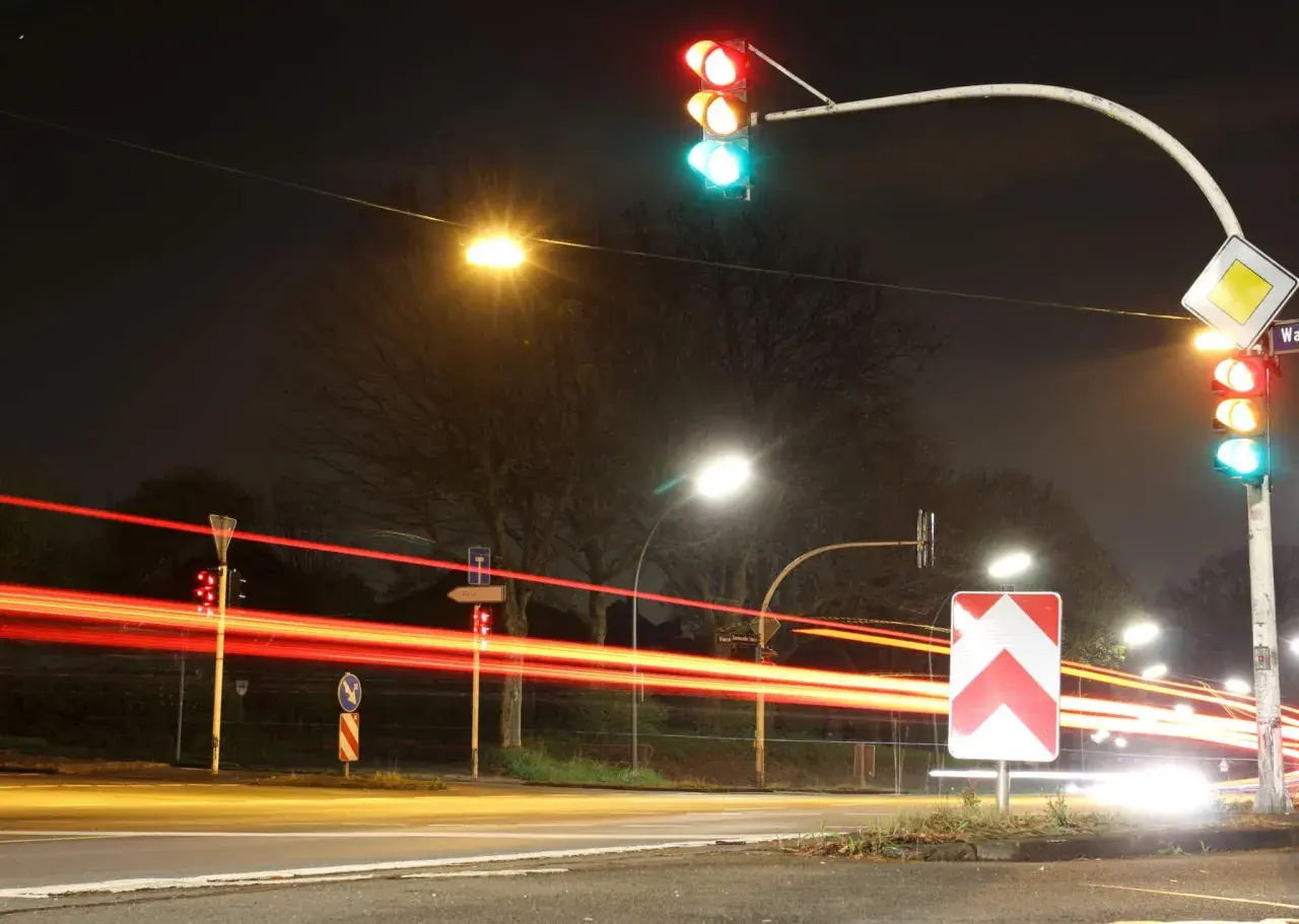 Rote Ampel, Blitzer, 2 mal geblitzt. Lichtspuren von Autos bei Nacht, rote Ampel leuchtet, Verkehrsschilder.