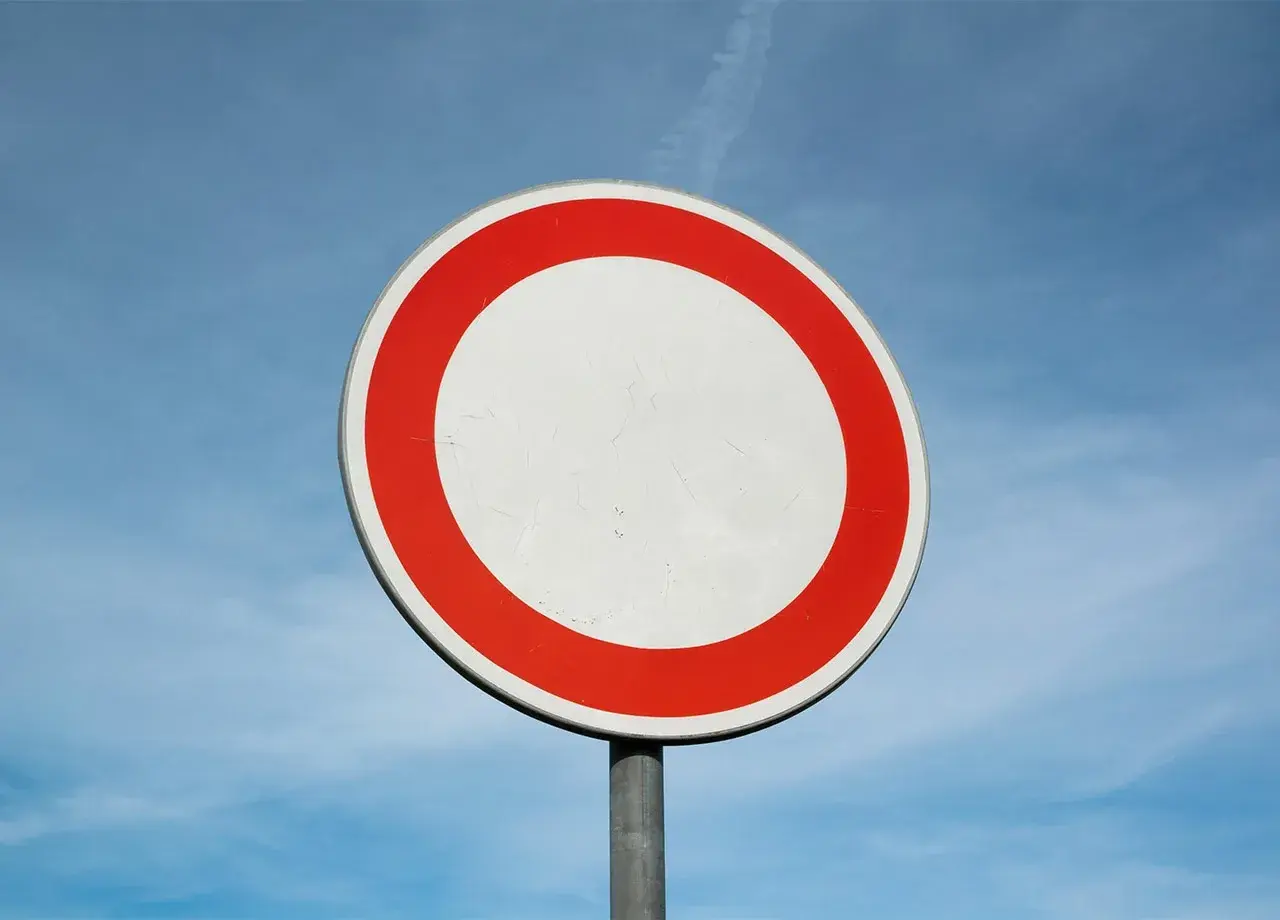 Verkehrsschild: Durchfahrt verboten, Strafe droht. Ein weißer Kreis mit rotem Rand vor blauem Himmel.