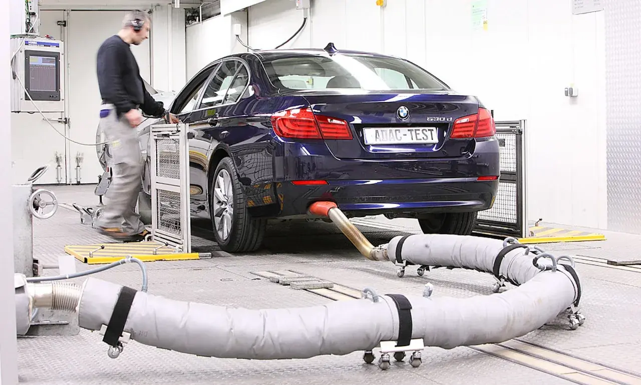 Blauer BMW auf einem Prüfstand, Abgasrohr angeschlossen für Euro 6c Tests. Ein Techniker überwacht die Messungen.