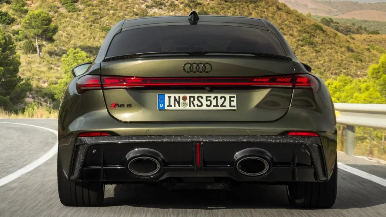 Ein Audi RS5 mit markantem Diffusor und ovalen Auspuffendrohren fährt auf einer kurvigen Straße.