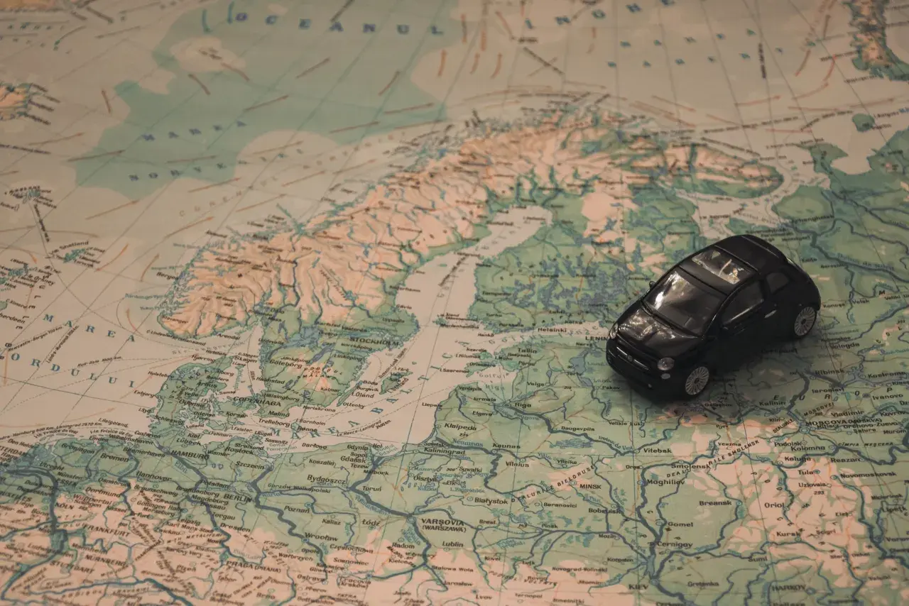 Kleines schwarzes Auto auf einer Europakarte. Die Reise beginnt, aber die Promillegrenze Frankreich ist zu beachten.