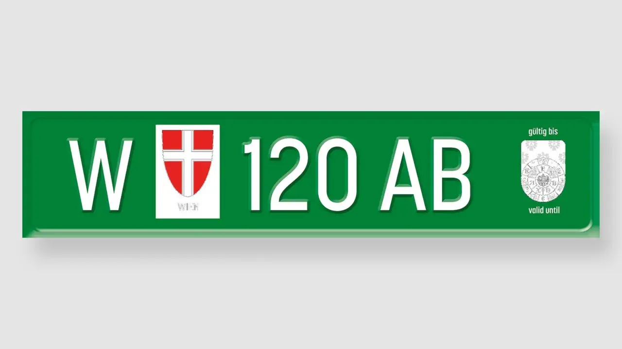 Grünes Wiener Kennzeichen "W 120 AB" mit Wappen und Prüfplakette.