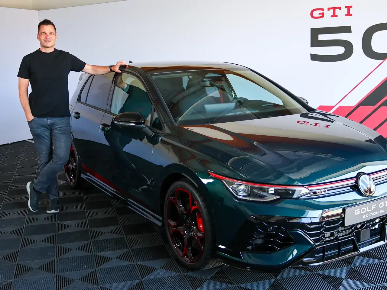 Mann neben dem schnellsten Golf der Welt, einem dunkelgrünen GTI Edition 50 mit roten Akzenten.