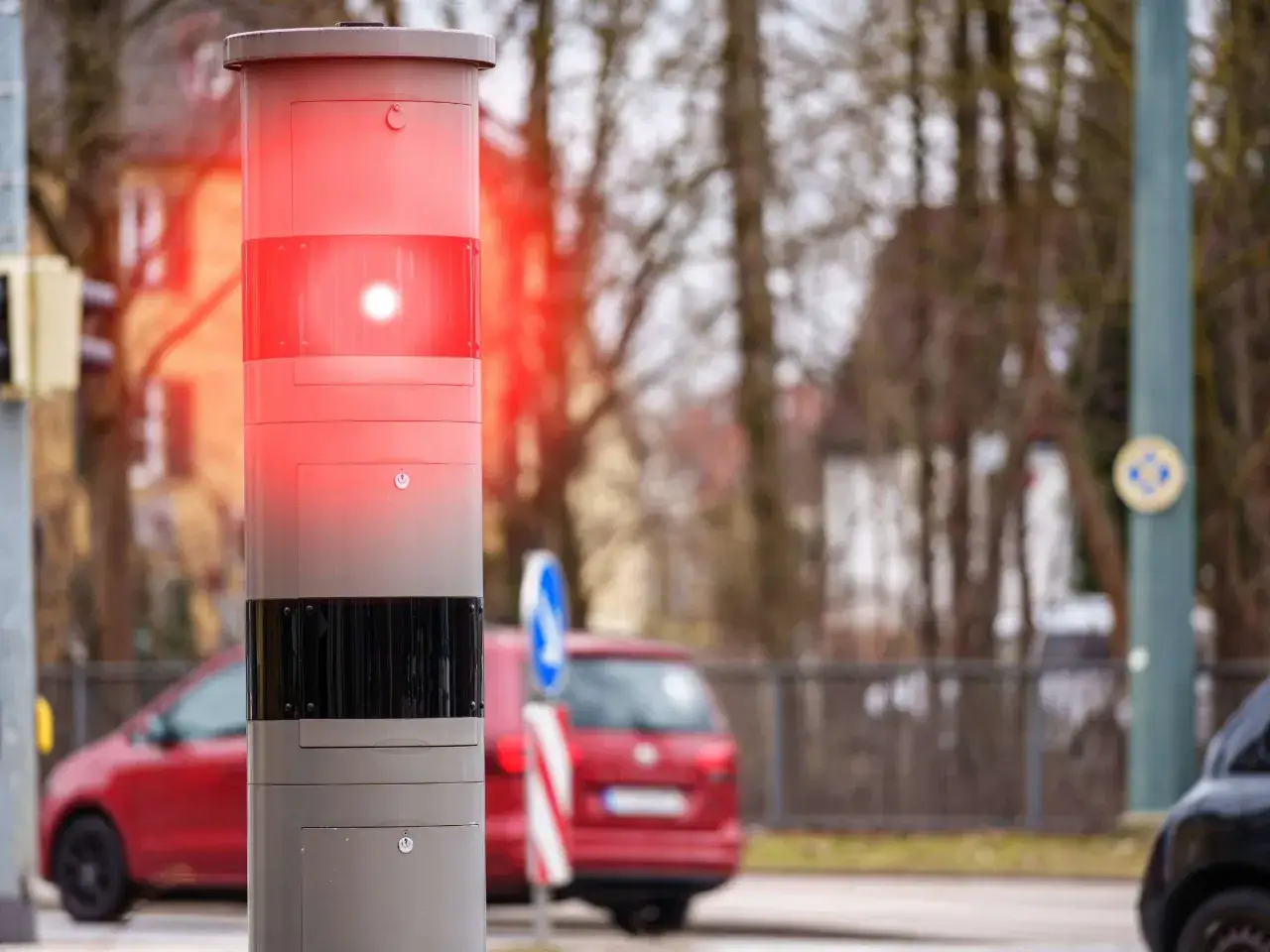 Blitzermarathon Hessen: Rote Blitzlichter an einem Messger&auml;t warnen Autofahrer. Ein rotes Auto f&auml;hrt vorbei.