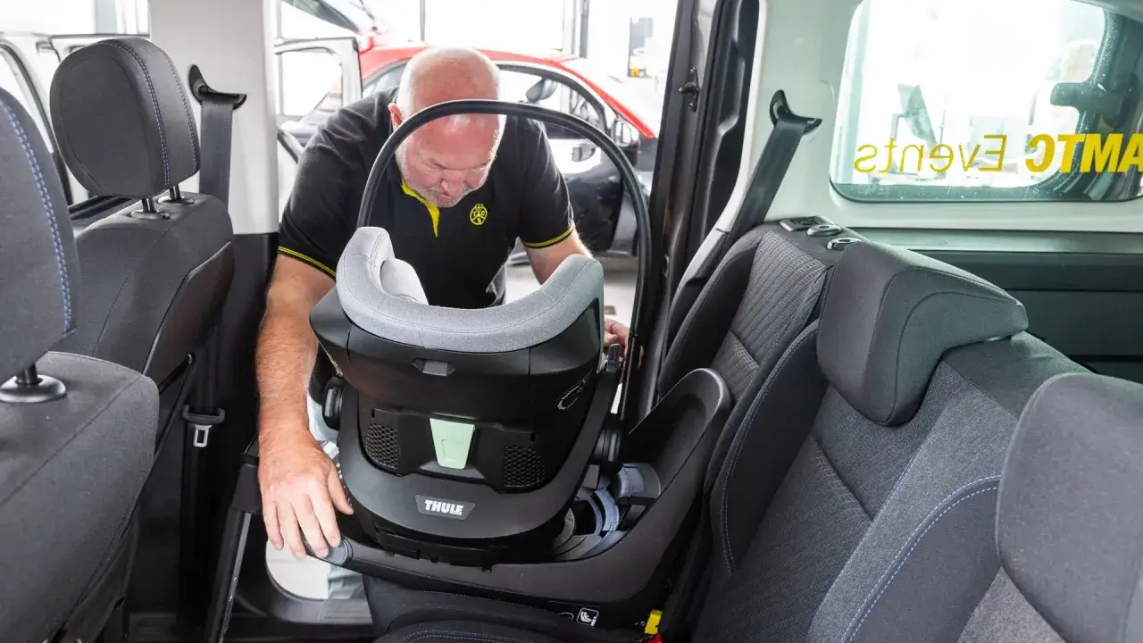 Mann installiert Kindersitz im Auto. Perfekt f&uuml;r die Reise nach Italien mit der Familie.