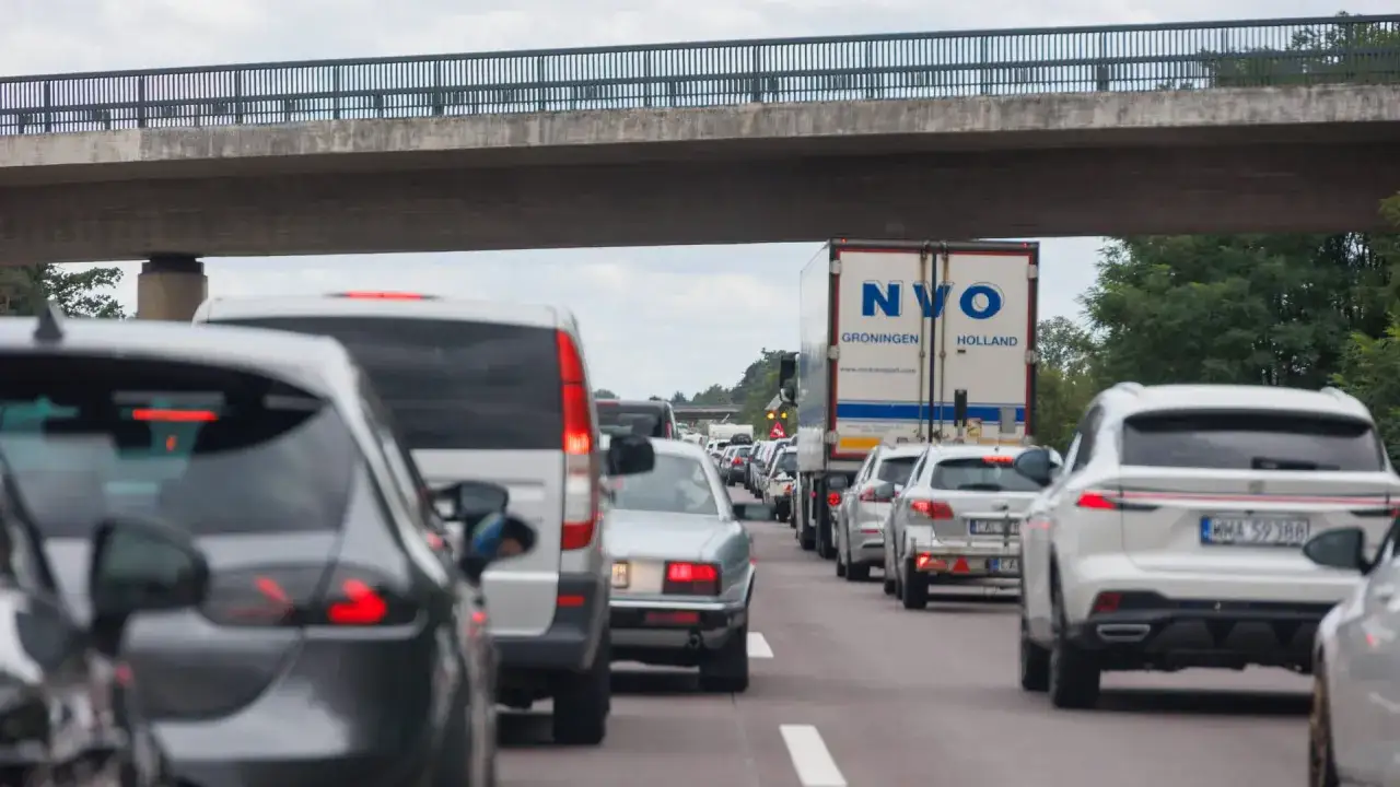 Stau auf der Autobahn, typischer reiseverkehr am wochenende. Viele Autos und ein LKW stehen unter einer Brücke.