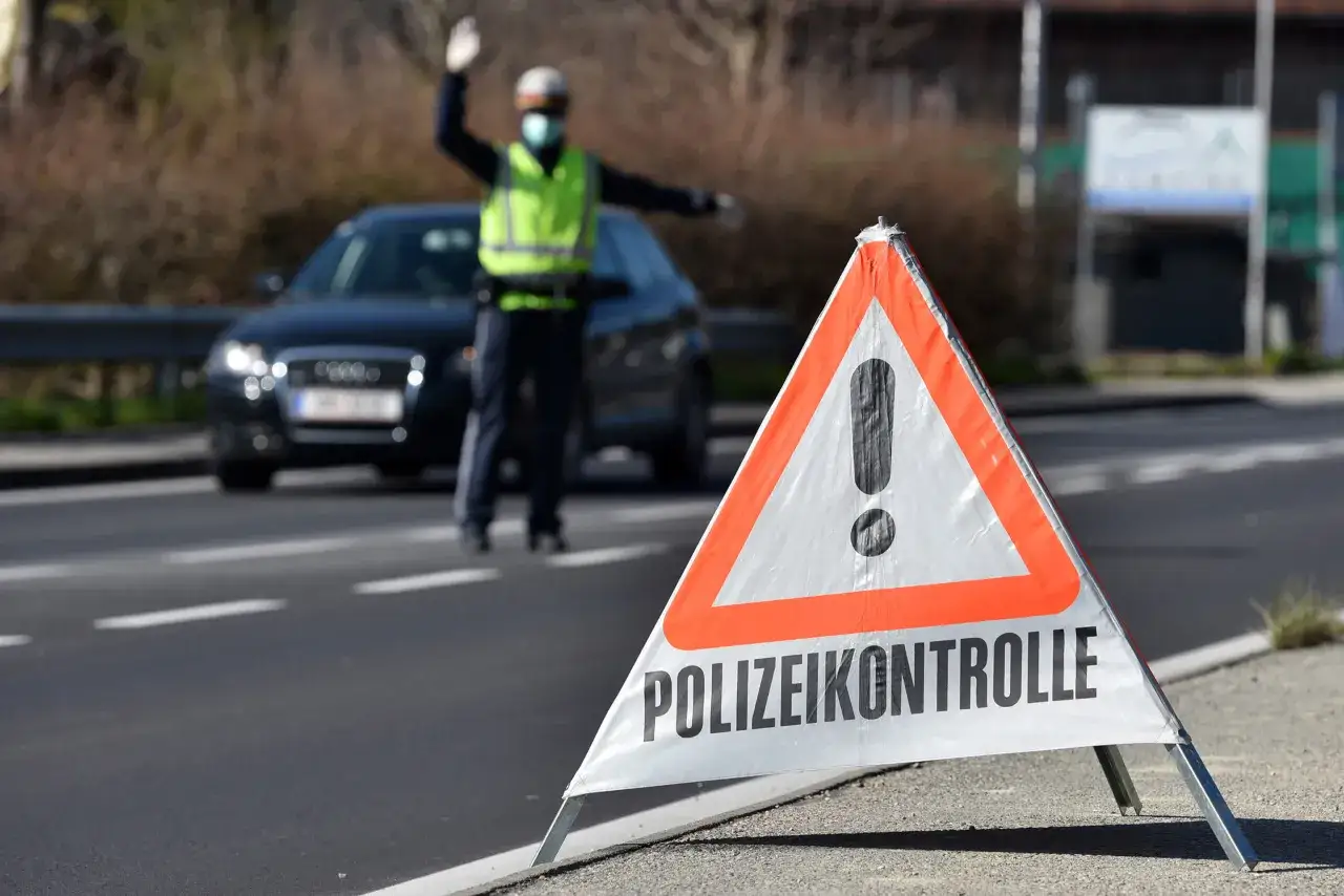 Polizeikontrolle: Ein Polizist regelt den Verkehr. Ein Warnschild weist auf die Kontrolle hin, um Unfälle durch Alkohol am Steuer zu verhindern.