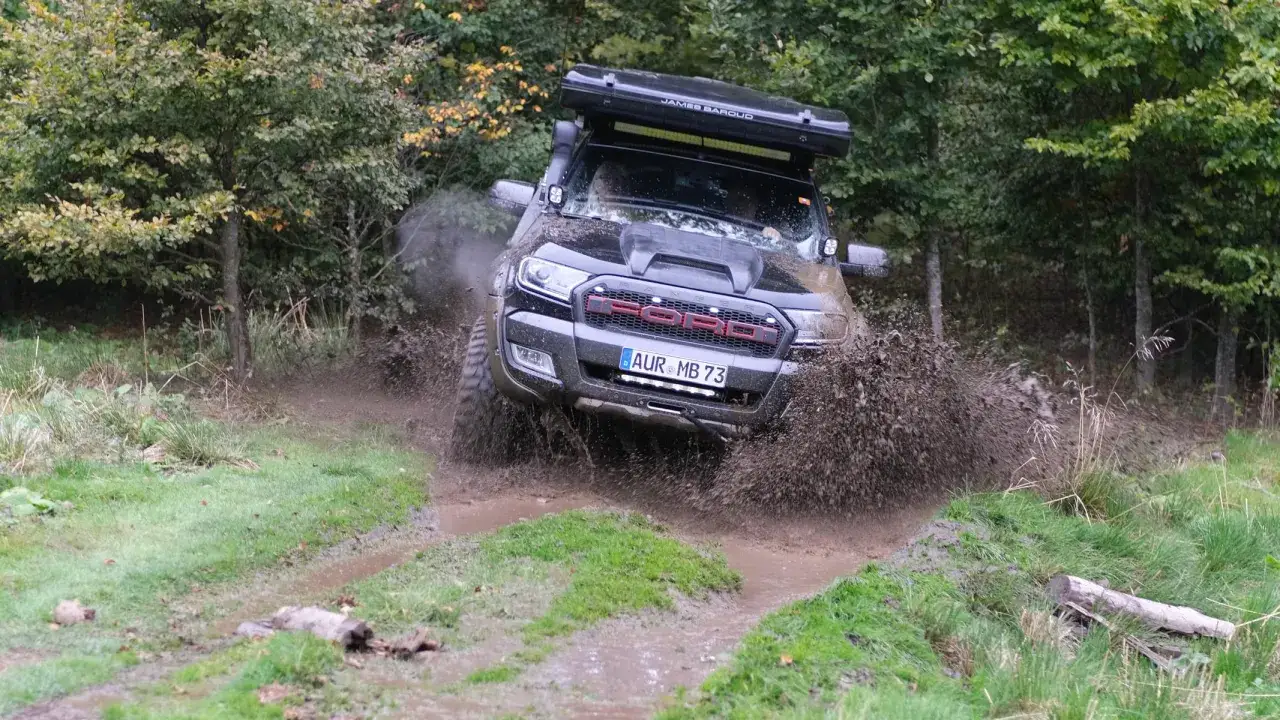 Ein schwarzer Gel&auml;ndewagen pfl&uuml;gt durch eine schlammige Pf&uuml;tze, was bedeutet offroad: Abenteuer abseits befestigter Wege.