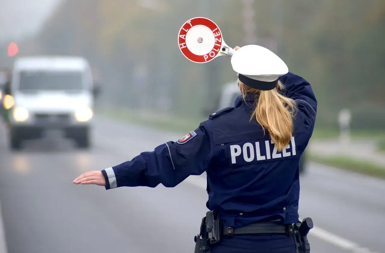 Polizistin stoppt Verkehr mit Stoppschild. Kontrollen zur Promillegrenze im Auto sind wichtig für die Sicherheit.